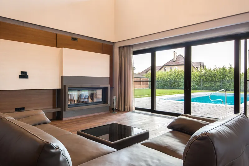 Living room with floor-to-ceiling sliding glass doors opening to a pool