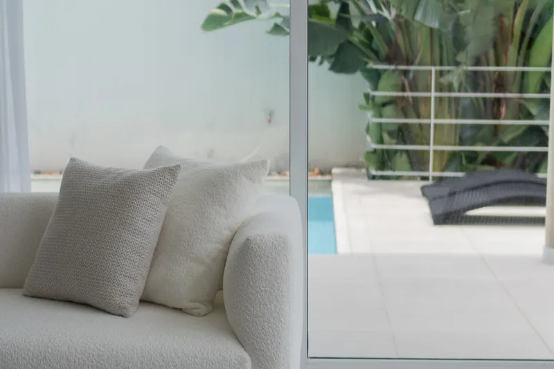 White coastal living room with large glass doors and a pool outside
