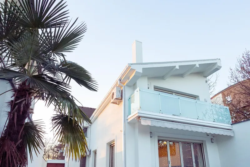 Modern white home with palm trees and large windows